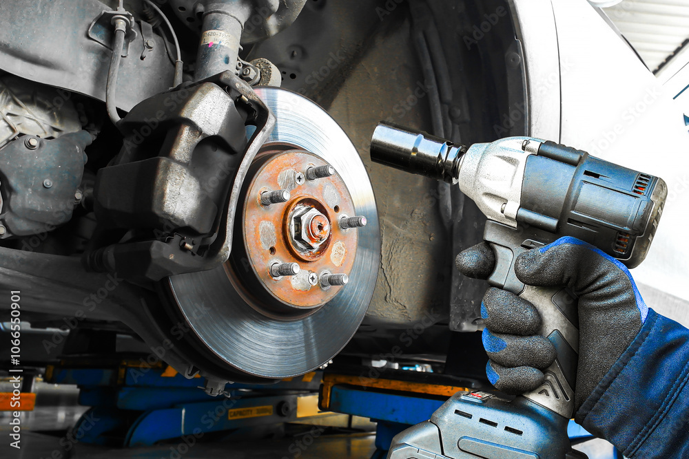 Car brake system repairing , close up of mechanic using impact wrench on car brake , Car repair concept