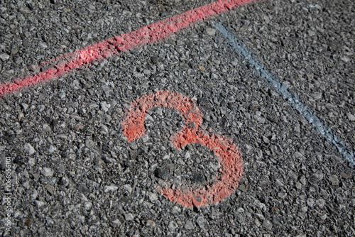 Grey street with red painted number three 3 and red and blue stripe