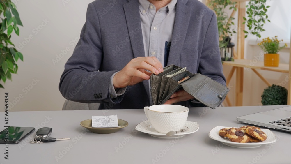 Man sitting at table at cafe restaurant opens wallet and paying bill with cash banknotes. Commercial business payments. Man sitting at table at cafe restaurant opens wallet and paying bill with cash banknotes. Commercial business payments.