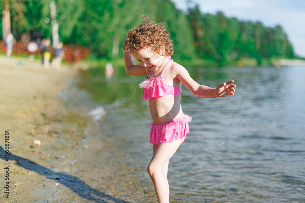 Cute girl playing on the beach with a sand and water on beach