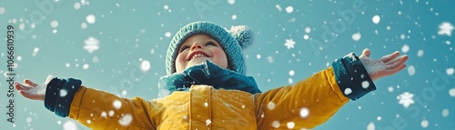 A young child in a yellow jacket catching snowflakes with their hands photo