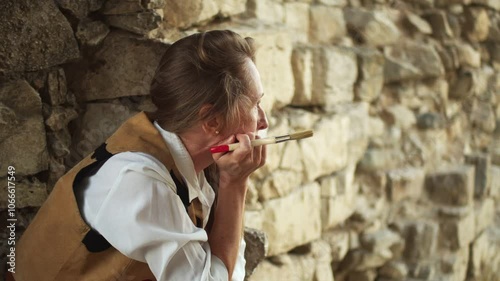 A female archaeologist with a brush is thinking in front of a fortress wall
