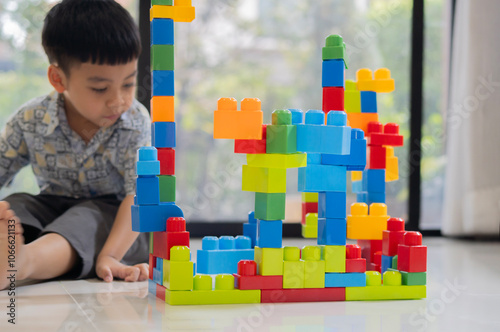 Child boy sitting on the floor in play room with color block and play constructing.