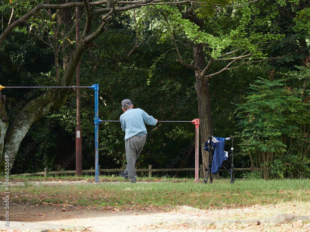 秋の公園で鉄棒を使ってリハビリするシニア男性の姿