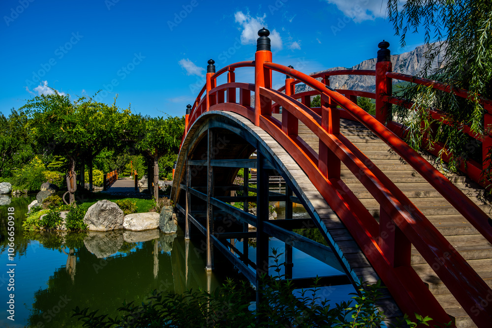 An oval wooden bridge over a pond in a Japanese garden. An oval wooden bridge over a pond in a Japanese garden.