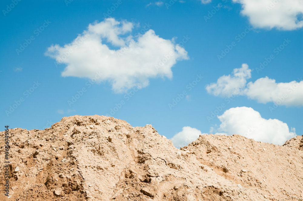 a mountain of sand against a blue sky and clouds a mountain of sand against a blue sky and clouds