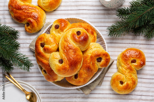 Festive table with homemade swedish St Lucia saffron buns. Also called  lussekatt or lussebulle, Cornish tea treat bun or revel bun, sweet bun flavoured with saffron and contains dried raisins.  photo