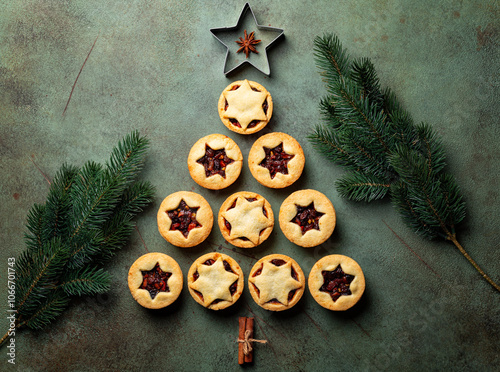 Christmas food Background with fir tree made from traditional christmas Mince pies, anise stars and cinnamon stickes on a green table surface.