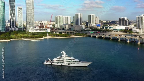 Aerial view shows a luxurious yacht sailing through Miami's turquoise waters of biscayne bay, framed by skyscrapers and vibrant city life, creating a relaxed atmosphere for tourists and locals. USA
