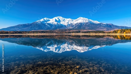 Snow-Capped Mountains Reflected in a Crystal Clear Lake Under a Bright Blue Sky