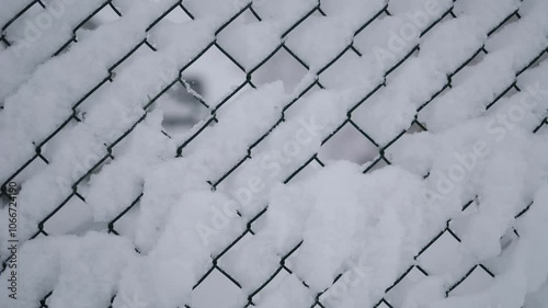 Snow-covered chain-link fence, focusing on the geometric patterns created by the snow buildup