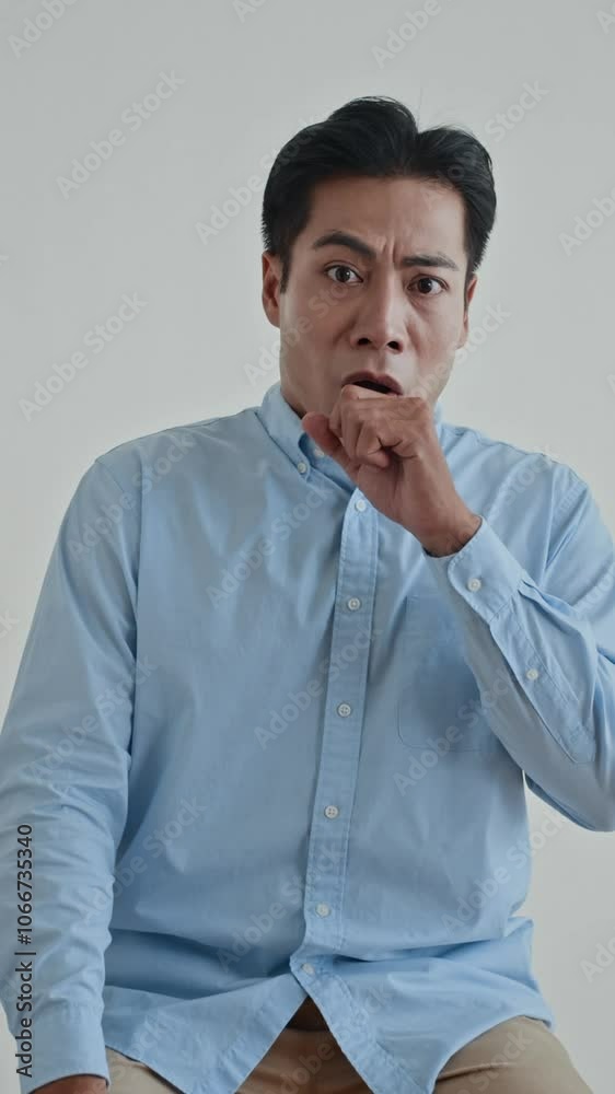 Vertical shot of Asian guy feeling shocked while looking at camera on white background Vertical shot of Asian guy feeling shocked while looking at camera on white background