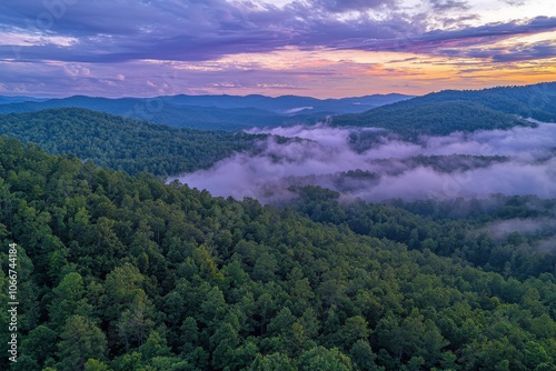 A breathtaking aerial view of lush green mountains shrouded in mist during sunset, showcasing nature's beauty and tranquility.