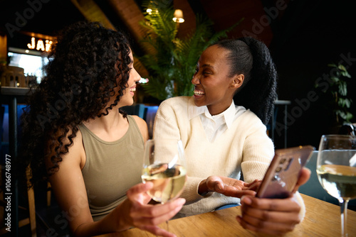 A black and Caucasian friend laughing at the photo they took together photo