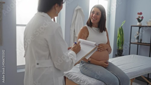 Wallpaper Mural Pregnant woman and female doctor in a clinic discussing medical notes during a prenatal checkup with bright indoor setting. Torontodigital.ca