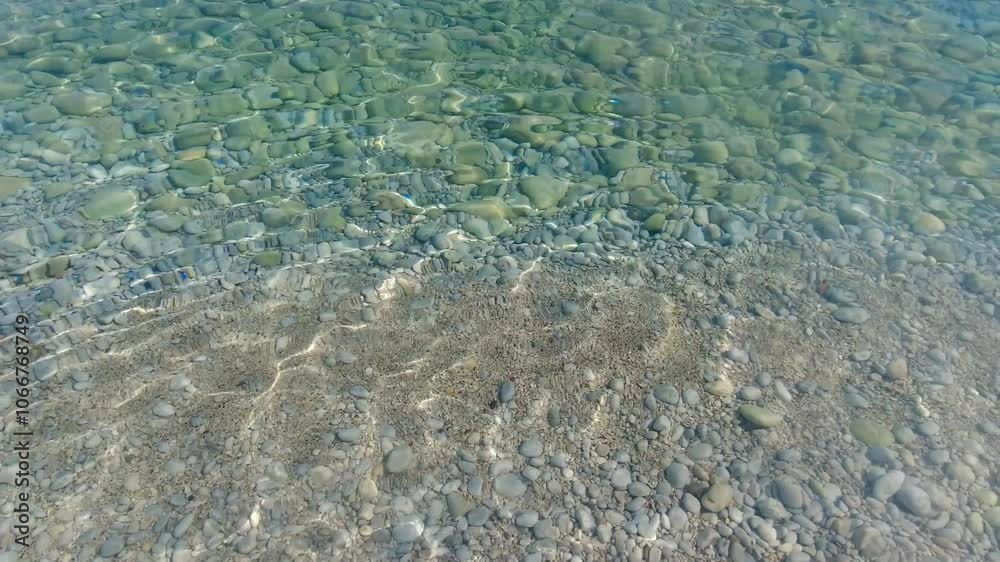 Crystal clear ocean water as seen from beach with stones and sand Crystal clear ocean water as seen from beach with stones and sand