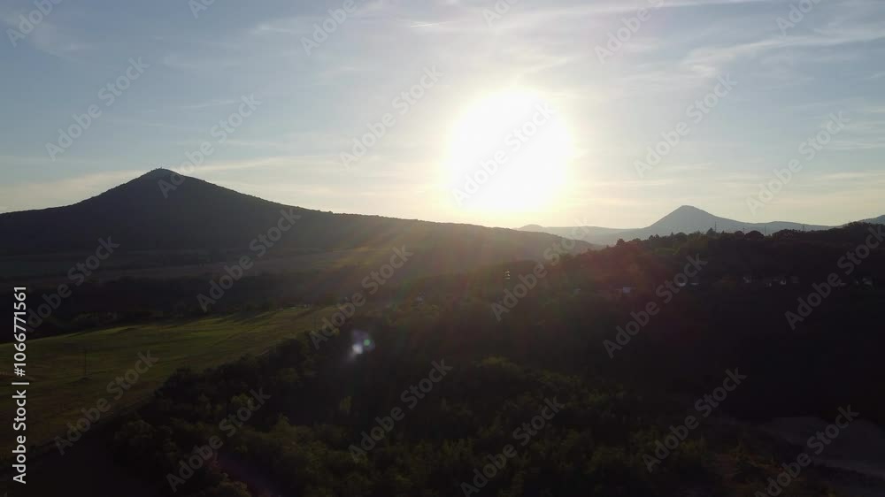 Drone sunset view over rolling hills and mountains in the Czech Republic, with warm sunlight and subtle rays casting over a rural valley, creating a calm and serene atmosphere Drone sunset view over rolling hills and mountains in the Czech Republic, with warm sunlight and subtle rays casting over a rural valley, creating a calm and serene atmosphere