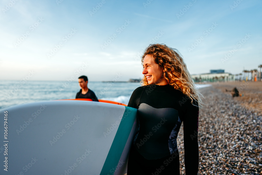 Fit couple surfing at sunset. Friends having fun inside ocean. Extreme sport and vacation concept Fit couple surfing at sunset. Friends having fun inside ocean. Extreme sport and vacation concept