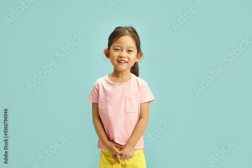 Smiling Chinese appearanceed Child Girl in Casual Summer Outfit Cheerful Stands Over Blue Isolated, Studio Portrait photo