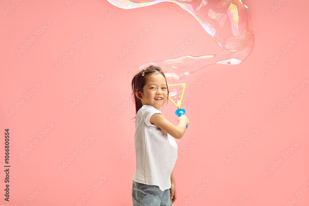 Lovely and Happy Little Girl Blowing Large Soap Bubble Around of Herself Standing on Pink Isolated Background Lovely and Happy Little Girl Blowing Large Soap Bubble Around of Herself Standing on Pink Isolated Background