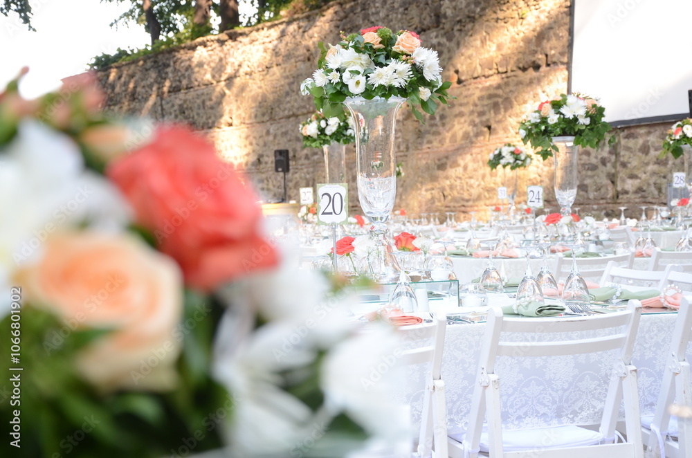 Rustic outdoor wedding reception with round tables, white linens, and floral centerpieces