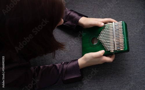 Girl playing kalimba with close-up on kalimba keys, enjoying soothing sound of this thumb piano. Kalimba, also known as mbira or thumb piano. African musical instrument photo