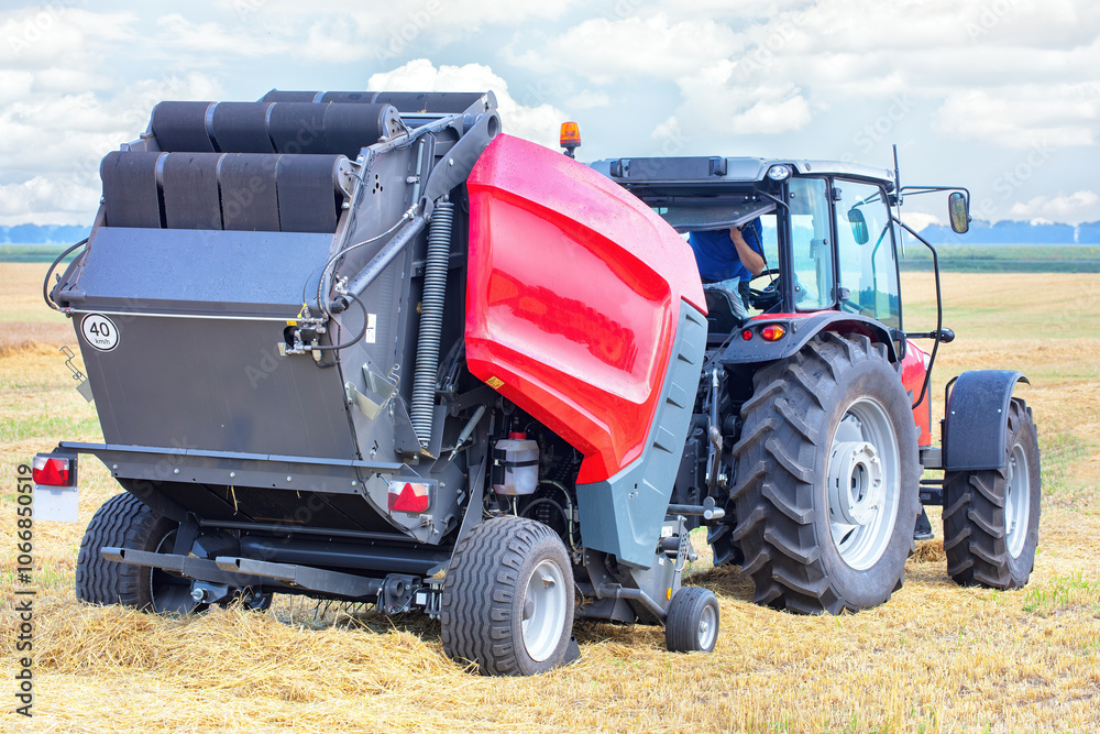 A tractor baling hay under a bright sky in a lush field on a sunny afternoon