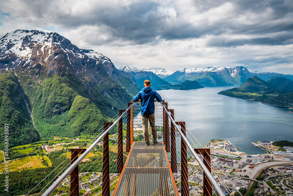 Man in blue standing on Rampestreken viewpoint over mountains in Norway Man in blue standing on Rampestreken viewpoint over mountains in Norway