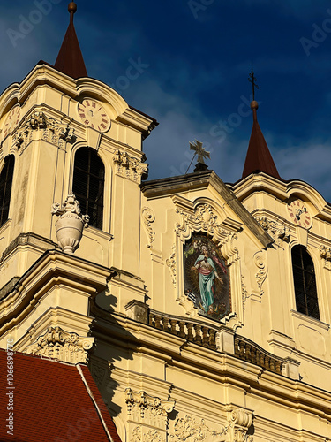 Elegant church facade with clock tower and religious artwork in Rajhrad, Czech Republic. photo