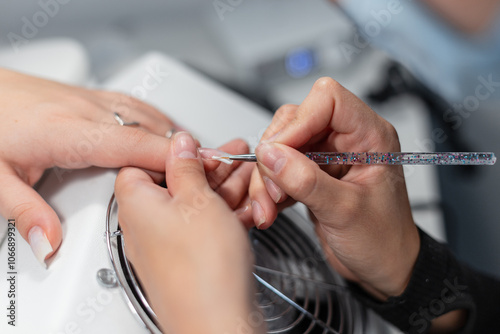 A professional woman manicurist does a manicure in a beauty salon and applies nail polish with a brush. Hand care and beauty