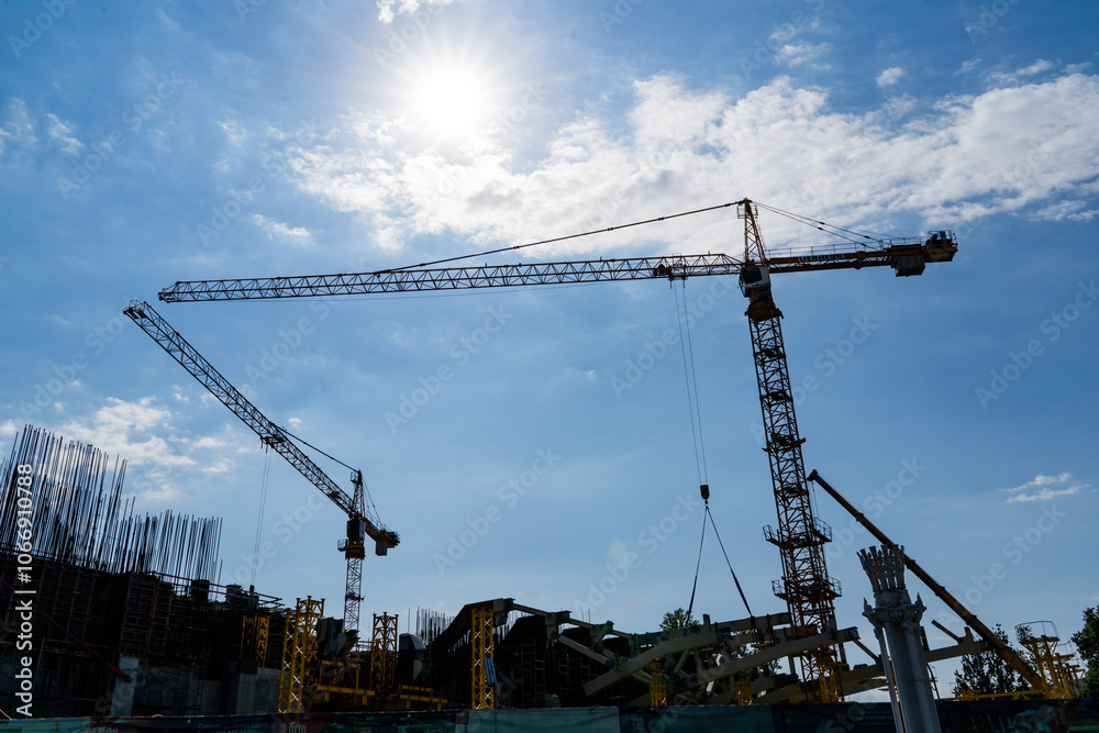 Silhouette of Construction Cranes Set Against a Bright Blue Sky During Daytime Hours