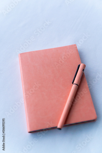 Obraz na płótnie A beautifully designed pink notebook elegantly paired with a matching pen artfully placed on a textured surface. w salonie