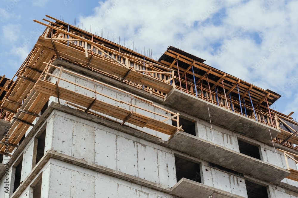 The ongoing construction of a multistory building features cranes and scaffolding raised overhead