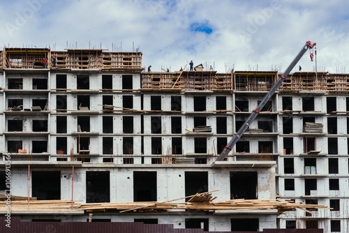 The ongoing construction of a multistory building features cranes and scaffolding raised overhead