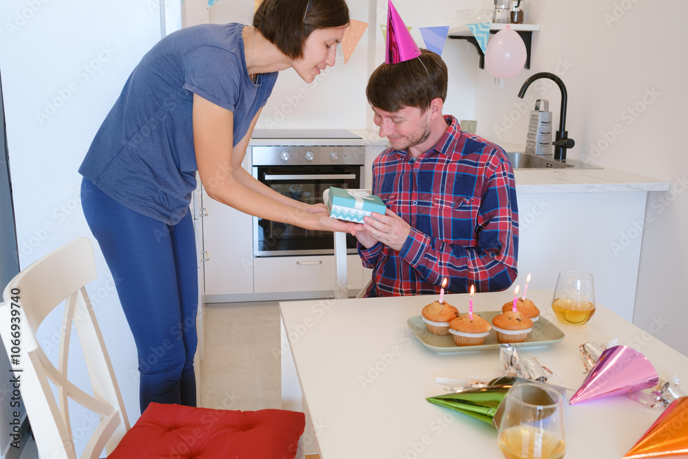 Fototapeta premium family exchanges gifts in dining room beautifully decorated for birthday celebration. The setting is filled with festive decorations and warm, joyful atmosphere, marking special occasion together.