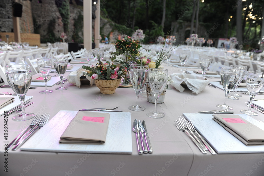 Beautiful Wedding Decor: Tables with Lush Floral Arrangements and Candles Outdoors at Evening