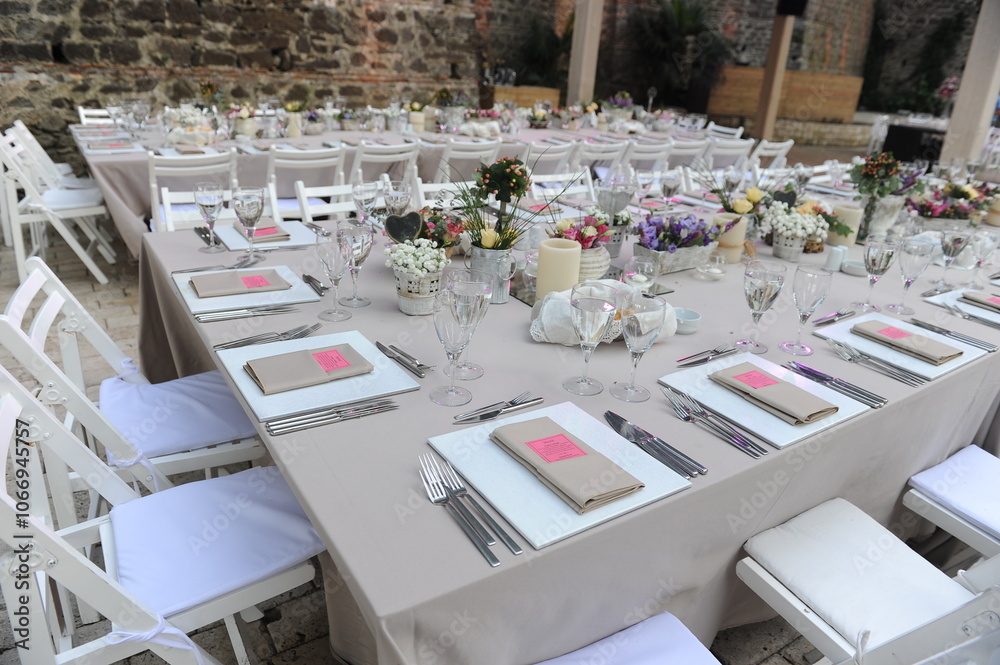 Beautiful Wedding Decor: Tables with Lush Floral Arrangements and Candles Outdoors at Evening