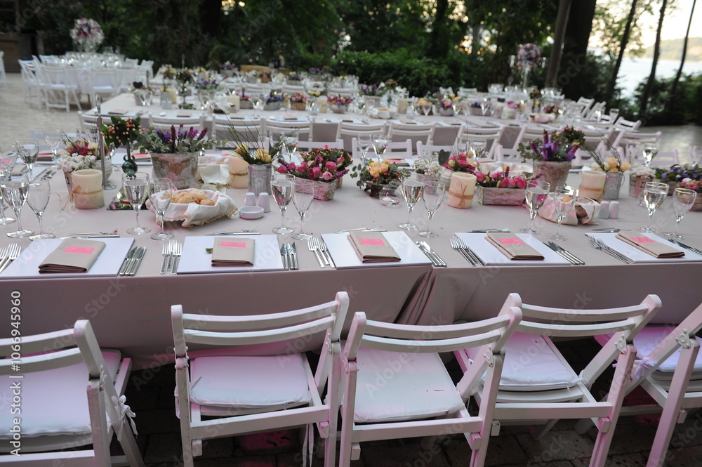 Beautiful Wedding Decor: Tables with Lush Floral Arrangements and Candles Outdoors at Evening