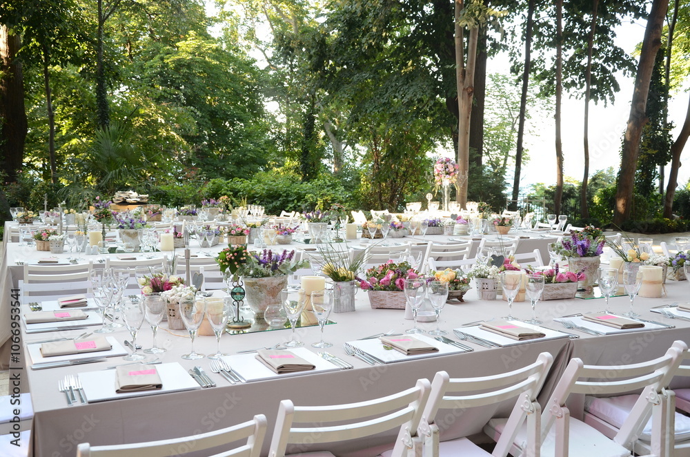 Beautiful Wedding Decor: Tables with Lush Floral Arrangements and Candles Outdoors at Evening