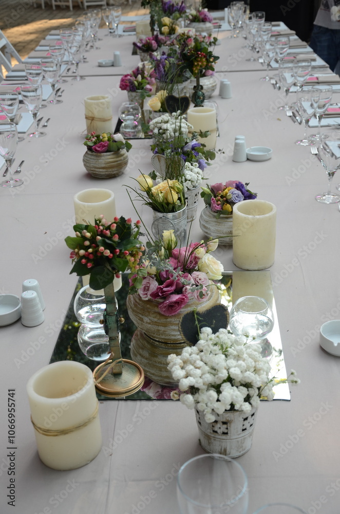 Beautiful Wedding Decor: Tables with Lush Floral Arrangements and Candles Outdoors at Evening