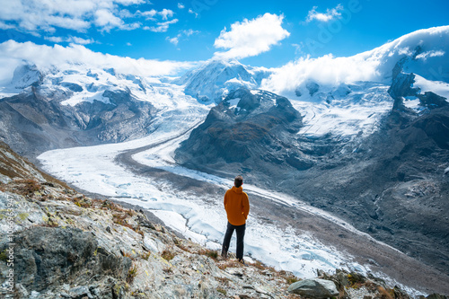 Traveler enjoying the landscape on top of a mountain, with a glacier, in Switzerland.