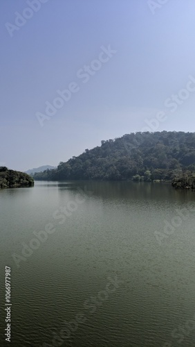 Serene lake surrounded by green hills under a clear sky.