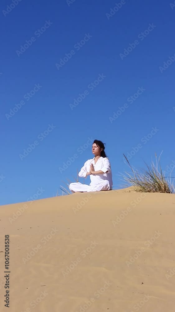 young caucasian woman practices lotus position of yoga on sand hill young caucasian woman practices lotus position of yoga on sand hill
