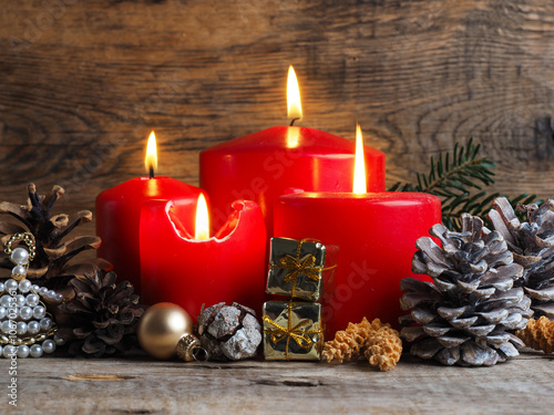 Red Advent candles on a rustic wooden background, fourth candle is burning photo