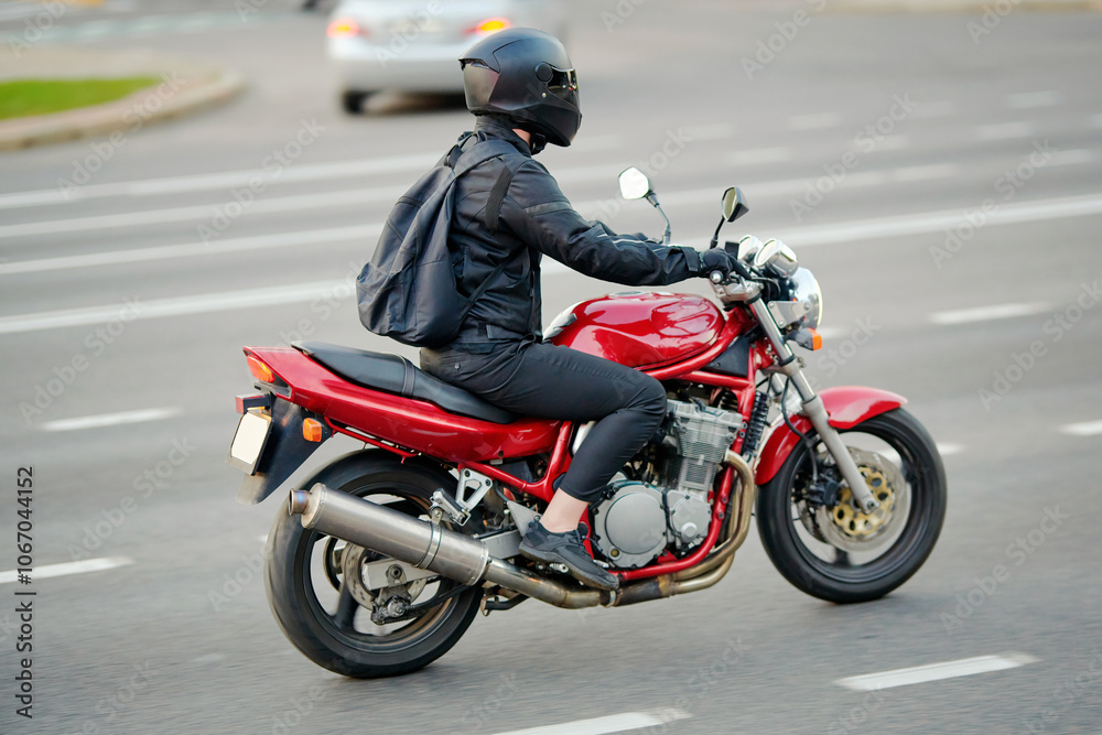 Man on red motorcycle cruising down city road, thrill of city riding and the lifestyle of motorcyclist. Motorcyclist in protective helmet on motorbike riding. Selective focus, motion blur Man on red motorcycle cruising down city road, thrill of city riding and the lifestyle of motorcyclist. Motorcyclist in protective helmet on motorbike riding. Selective focus, motion blur