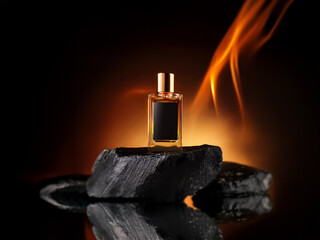 A small glass bottle of perfume sits on a black rock with an orange background behind it.