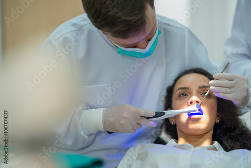 The dentist shines ultraviolet light to make the fluoride setting and cover patients' teeth in the dental clinic.