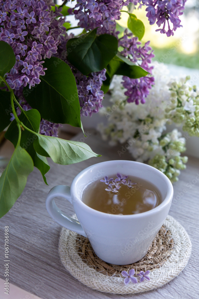 Tasty black tea in white cup on windowsill with aromatic lilac flowers. Spring composition Cup of lilac tea drinking recipe flowering branches of purple lilac. Still life for copy space greeting card Tasty black tea in white cup on windowsill with aromatic lilac flowers. Spring composition Cup of lilac tea drinking recipe flowering branches of purple lilac. Still life for copy space greeting card