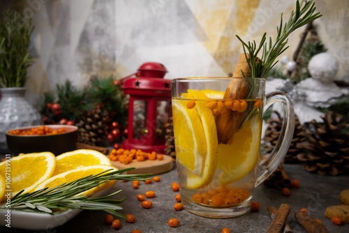 A cup of tea with buckthron berries, cinnamon sticks, rosemary, orange Christmas decor photo