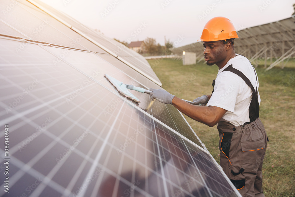 African American Male Technician Cleaning Solar Panels for Optimal Energy Efficiency